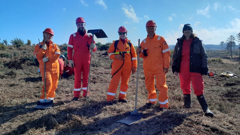 Rangers lining up with tools, behind them is an expanse of heathland.